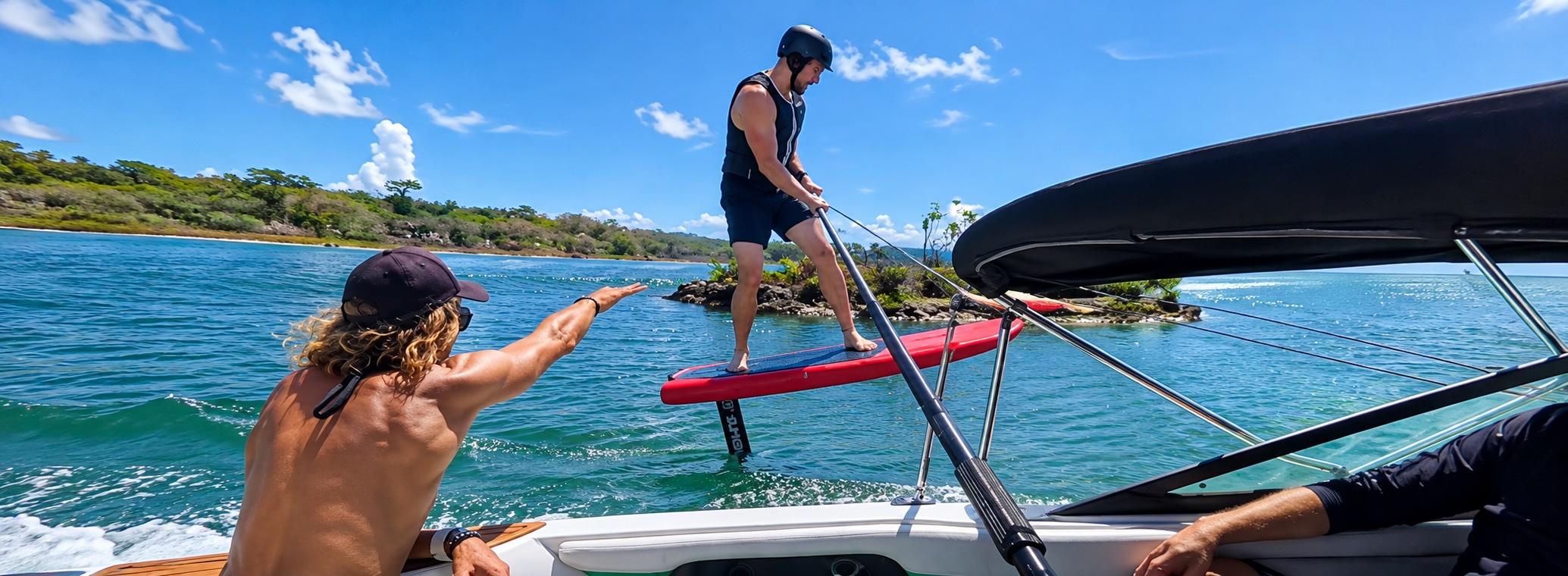 Instructor on the boat guiding a rider learning to hydrofoil behind the boat in the Riviera Maya