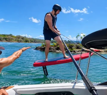Instructor on the boat guiding a rider learning to hydrofoil behind the boat in the Riviera Maya